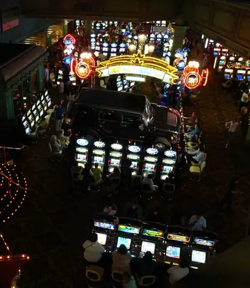 Players at glowing slot machines on a busy casino floor