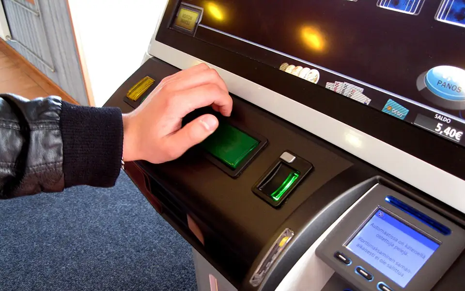Player pressing the button on a gaming machine next to a card payment reader